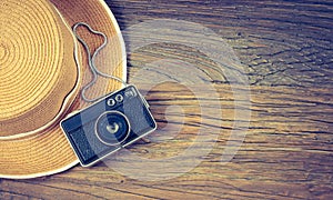 Summer hat and camera on wood. Vintage tone. Travel and vacation concept