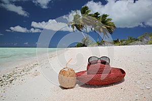 Summer hat and coconut on tropical sandy beach