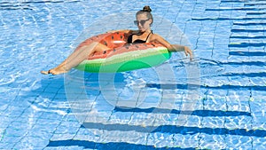 Summer hat pool. Young sexy woman with green inflatable ring in bikini swimsuit, sunglasses floating in blue water