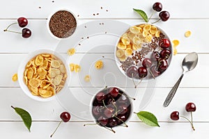 Summer healthy breakfast with corn flakes, greek yogurt, sweet cherry and flax seeds in bowl on white wooden table.