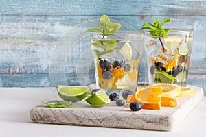 Summer healthy cocktails of citrus infused waters, lemonades or mojitos, with lime lemon orange blueberries and mint, diet detox