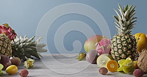 Summer healthy exotic passion fruits, pine apples and dragon fruit on a gray wooden table on a blue. Vegetarian healthy