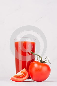 Summer healthy food and drink - pulpy red tomato juice, tomato and juicy piece in light white modern interior, vertical.