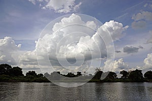 Summer heat. The Pripyat river in July. Clouds and sky. Oaks and trees on the shore. Reflection