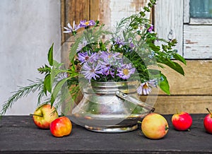 Summer herb bouquet with blooming lemon basil, radish flowers and asparagus sprigs in a metal sugar bowl and red-yellow