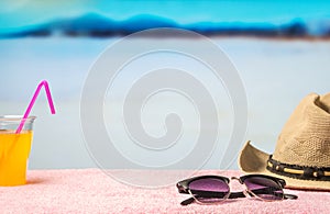 Summer holiday background with free empty blank copy space. Brimmed hat, sunglasses and yellow drink on towel in paradise lagoon. photo