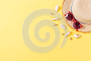 Summer holiday background with straw hat and seashells on yellow background top view with copy space