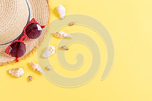 Summer holiday background with straw hat and seashells on yellow background top view with copy space