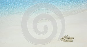 Summer holiday beach background with flip flops on a tropical beach. Slippers from a sand on a beach, holiday concept