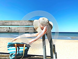 Summer holiday at beach ,women hat with bow beachwear  blue jeans on wooden bench  sky  with white clouds beach with white  sand ,