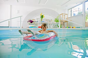 Summer holiday is comming. Happy little child girl playing in water with colorful child boat in swimming pool