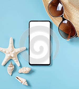 Summer holiday concept with hat, sunglasses, phone, sea shells and starfish on light blue summer background