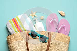 Summer holiday concept.Top view of beach bag with flip flops,beach towel,sunglasses,sea shells and starfish