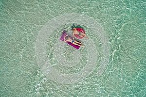 .Summer holiday fashion concept - tanning couple at the beach on a turquoise sea shot from above. Top view from drone. Aerial view