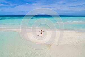 Summer holiday fashion concept - tanning girl wearing sun hat at the beach on a white sand shot from above.Top view from drone.