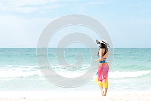 Summer Holiday. Lifestyle woman chill holding big white hat and wearing bikini fashion summer trips walking on the sandy ocean bea photo