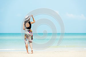 Summer Holiday. Lifestyle woman chill holding big white hat and wearing dress fashion summer trips standing chill on the sandy oce photo