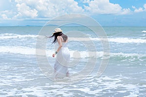 Summer Holiday. Lifestyle woman white dress wearing fashion summer trips walking on the sandy ocean beach. Happy woman enjoy and r