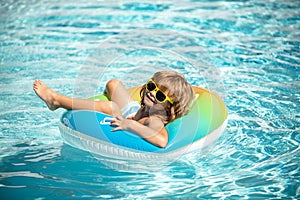 Summer holiday. Summertime kids weekend. Child in swiming pool. Funny boy on inflatable rubber circle at aquapark.