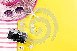 Summer holiday, travel and vacation concept. Retro film camera, sunglasses, starfish, beach hat and sea shell on yellow background