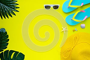 Summer holiday of traveler women. Top view from above of beach accessories and a hat with sunglasses and sandals on yellow backgro