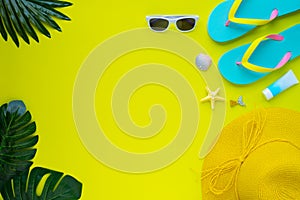 Summer holiday of traveler women. Top view from above of beach accessories and a hat with sunglasses and sandals on yellow backgro
