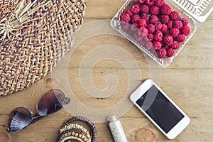 Summer holiday, vacation, relaxation concept. Raspberries, straw hat, smartphone, sunglasses from above, top view, flat