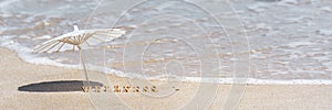 Summer holiday, vacation, sea wellness spa resort concept. Word wellness and beach umbrella on sand. Banner, copy space