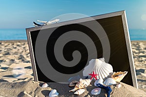 Summer holidays background. Starfish, seashells, toy plane and globe near blackboard on ocean nature beach. Design of summer