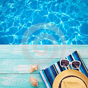 Summer Holidays in Beach Seashore. Fashion accessories summer flip flops, hat, sunglasses on bright turquoise board near the pool