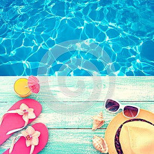 Summer Holidays in Beach Seashore. Fashion accessories summer flip flops, hat, sunglasses on bright turquoise board near the pool