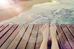 Summer holidays concept background with legs over wooden pier