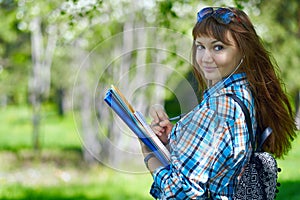 Summer holidays, education, campus and teenage concept - smiling female student with folders