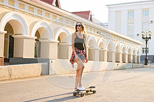 Summer holidays, extreme sport and people concept - happy girl riding skateboard on city street