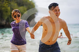 Summer holidays lifestyle portrait of young beautiful and sweet Asian Chinese couple in love running on the beach together