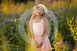 Summer holidays, nature, childhood, beauty. Portrait of child girl in hat in meadow, golden hour