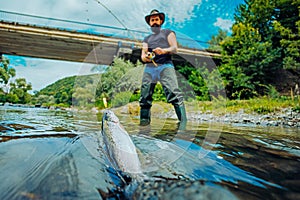 Summer holidays and people concept. Trout. A fisherman with fishing rod on the river. Fly fisherman using fly fishing