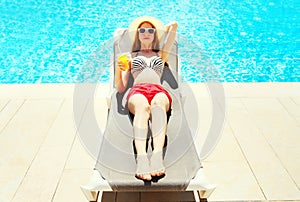 Summer holidays - pretty woman resting with juice from cup on a deckchair