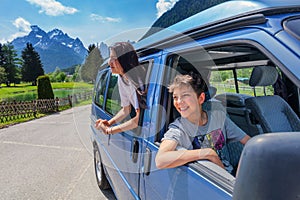 Summer holidays, road trip, vacation, travel and people concept - smiling child in minivan car in the mountains