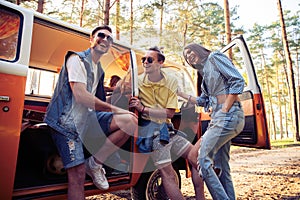 Summer holidays, road trip, vacation, travel and people concept - smiling young hippie friends having fun over minivan