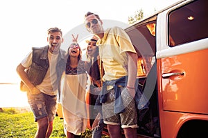 Summer holidays, road trip, vacation, travel and people concept - smiling young hippie friends having fun over minivan