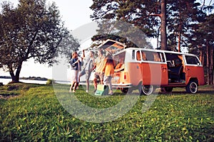 Summer holidays, road trip, vacation, travel and people concept - smiling young hippie friends having fun over minivan