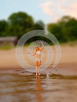 Summer holidays, vacation and beach concept - blonde girl in white bikini posing on the beach. Background blur