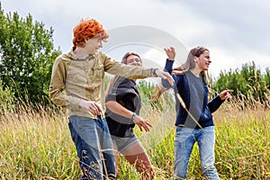 Summer holidays vacation happy people concept. Group of three friends boy and two girls dancing and having fun together outdoors.