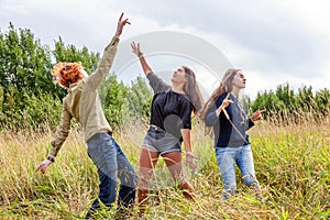 Summer holidays vacation happy people concept. Group of three friends boy and two girls dancing and having fun together outdoors.