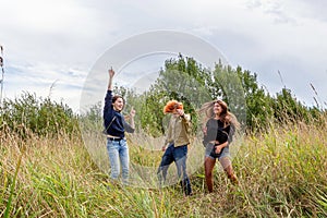 Summer holidays vacation happy people concept. Group of three friends boy and two girls dancing and having fun together outdoors.