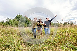 Summer holidays vacation happy people concept. Group of three friends boy and two girls running and having fun together outdoors.