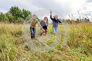 Summer holidays vacation happy people concept. Group of three friends boy and two girls running and having fun together outdoors.