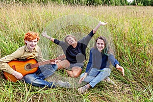 Summer holidays vacation music happy people concept. Group of three friends boy and two girls with guitar singing song having fun