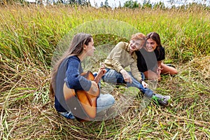 Summer holidays vacation music happy people concept. Group of three friends boy and two girls with guitar singing song having fun